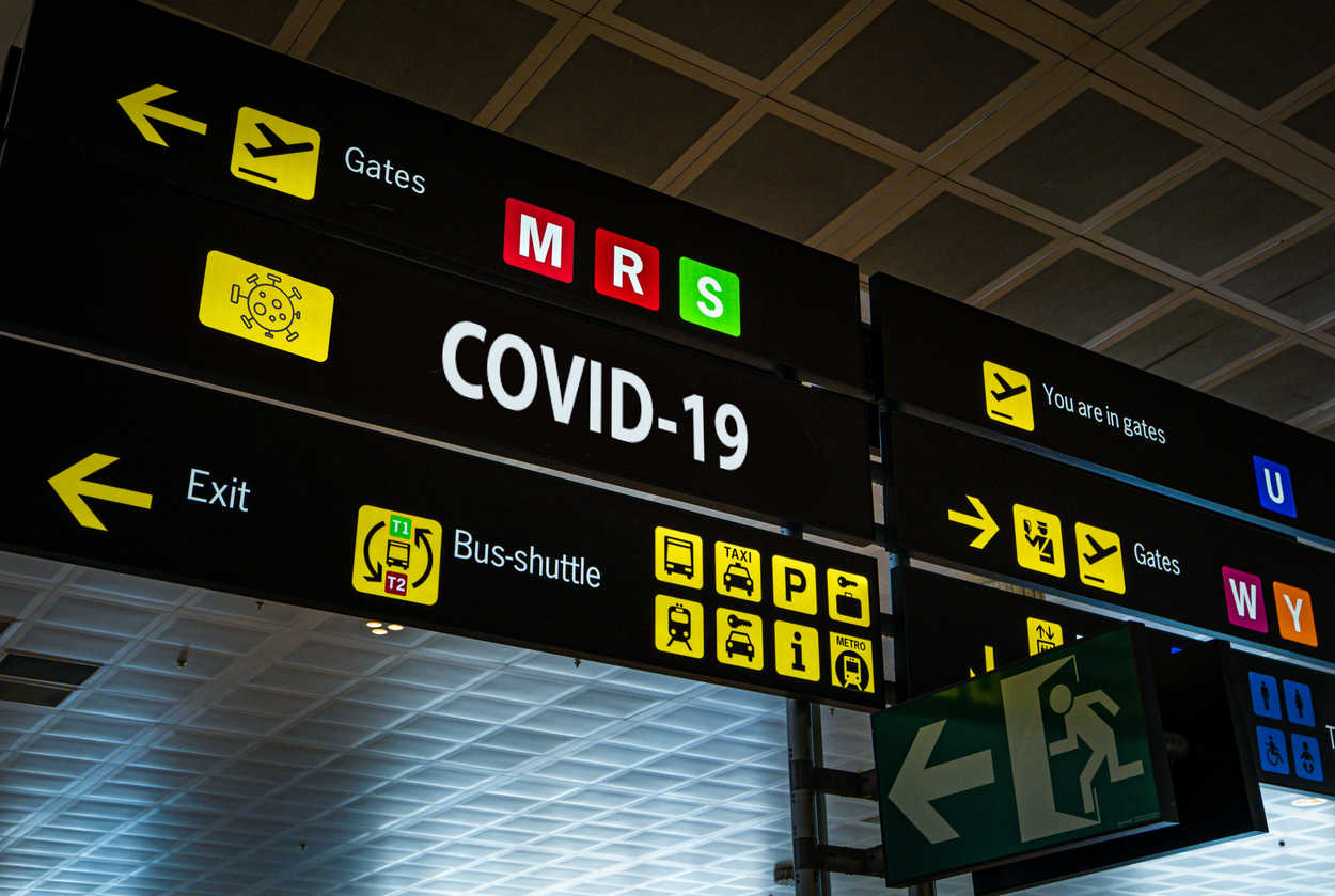 Information panel with Covid-19 wording at an international airport, symbolizing the global spread of the coronavirus through global air travel.