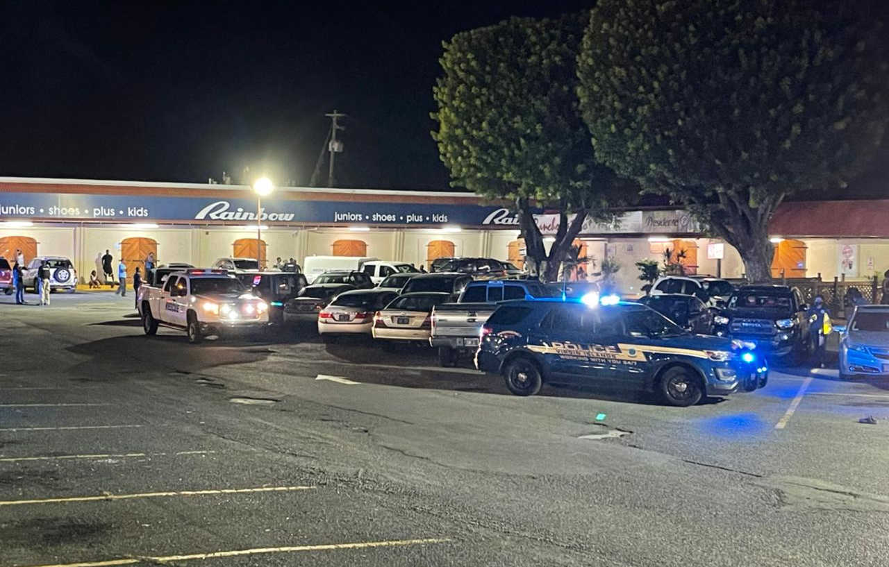 Police officers and personnel from the Medical Examiner’s Office at Vitraco Mall, where two males were shot and killed.