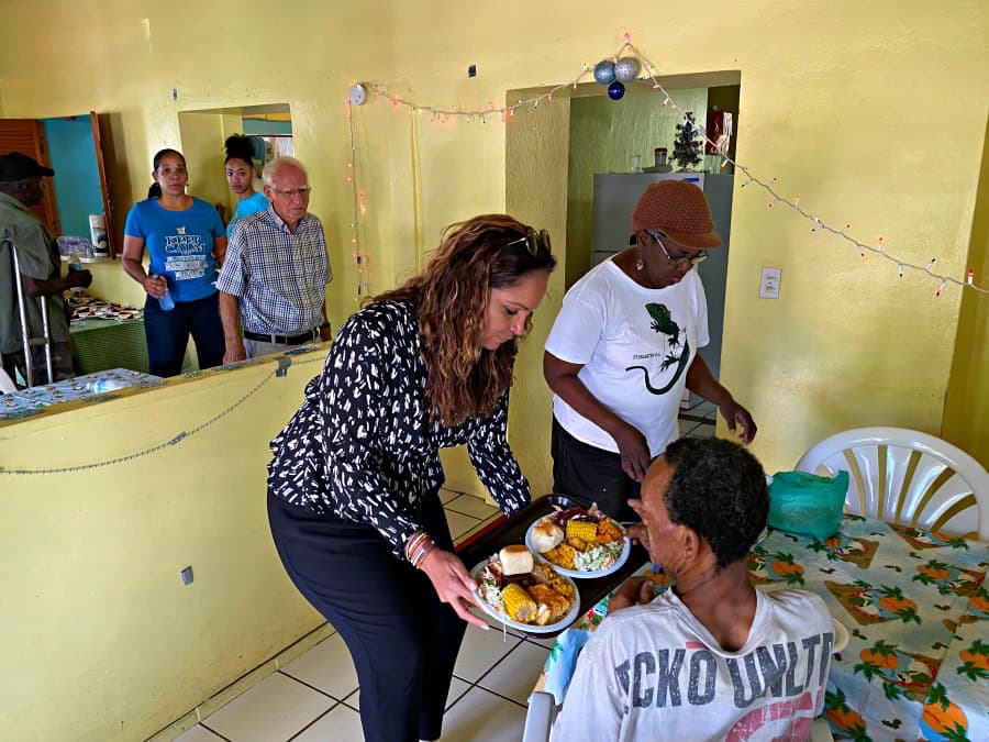 First Lady Yolanda Bryan serves a meal to elderly man