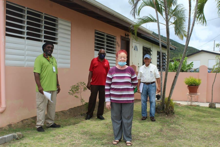 Homeowner Aracelis Cepeda (front, center), (left to right) Armand Corp. Project Manager Bevan Smith, VIHFA Construction Manager Michael Moreau and Uncle Nev Construction rep. Orlando Ramirez stand in front of Cepeda’s home in St. Croix slated to be repair