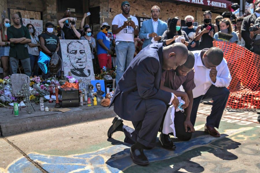 Quincy Mason, center, the son of George Floyd, and family attorney Ben Crump, left, kneel, Wednesday, June 3, 2020 as they visited the site of a memorial in Minneapolis where Floyd was arrested on May 25 and died while in police custody. Video shared onli