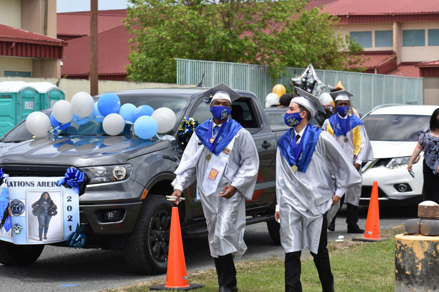 Students exit vehicles to receive diploma at a nearby stage.