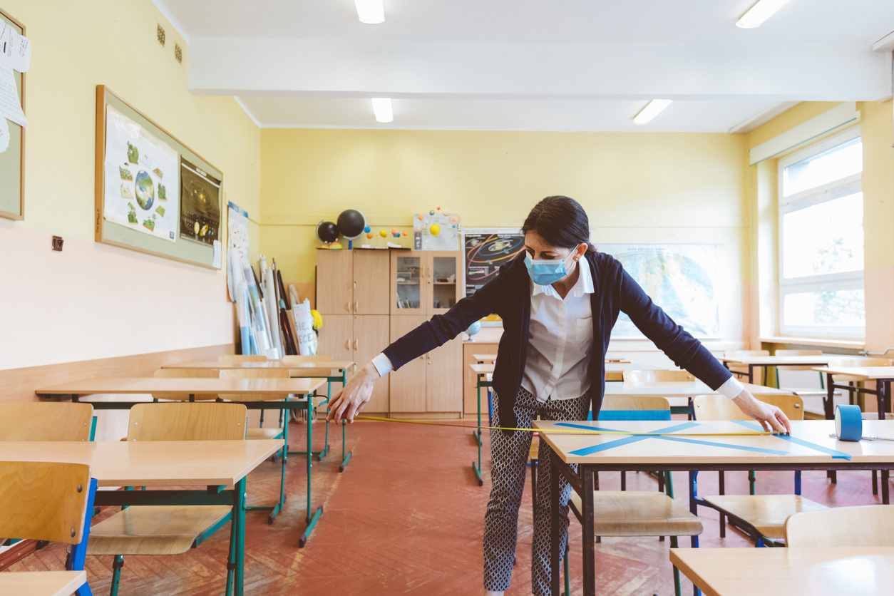 A teacher measuring a classroom for implementation of Covid-19 social-distancing protocols.