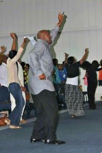 Pastor Reginald Perry, at Victorious Believers Ministries, dances alongside congregants at a service.