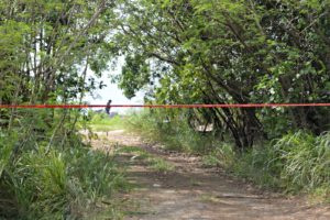 A police officer is seen in the distance investigating the crime scene at a beach in Hams Bluff, Frederiksted, where two police officers were shot to death on Wednesday night.