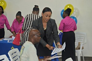 Millicent Aubain, Division of Personnel's territorial administrator of Recruitment and Classification, helps a job seeker fill an application.
