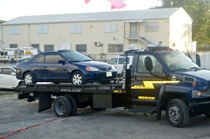 Police tow truck leaving crime scene with victim's car.