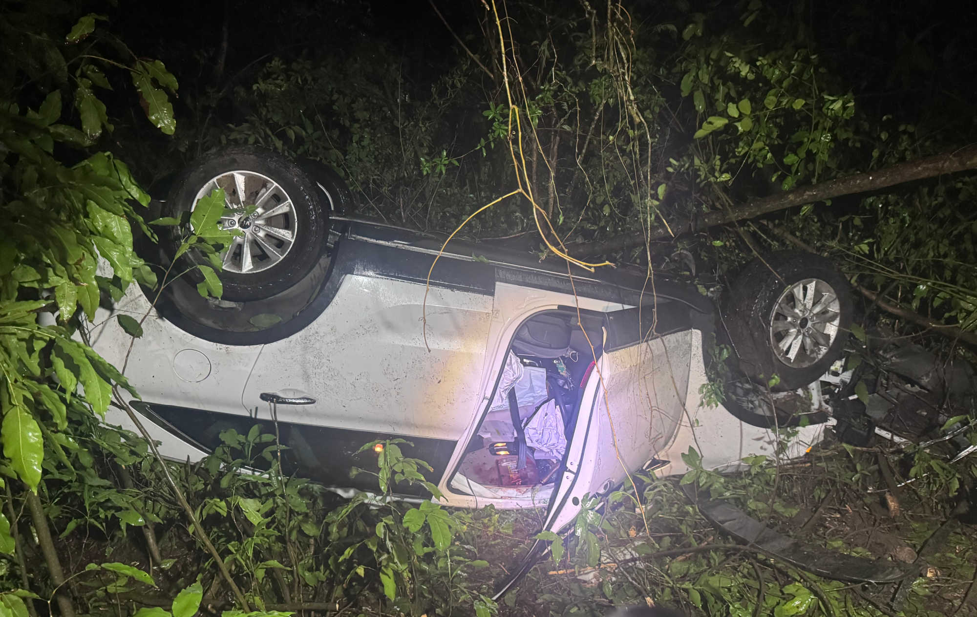 The white Kia Sorento driven by 96-year-old Donn B. Schindler lies overturned at the bottom of a wooded embankment in Salt River after Monday night’s fatal crash on St. Croix.