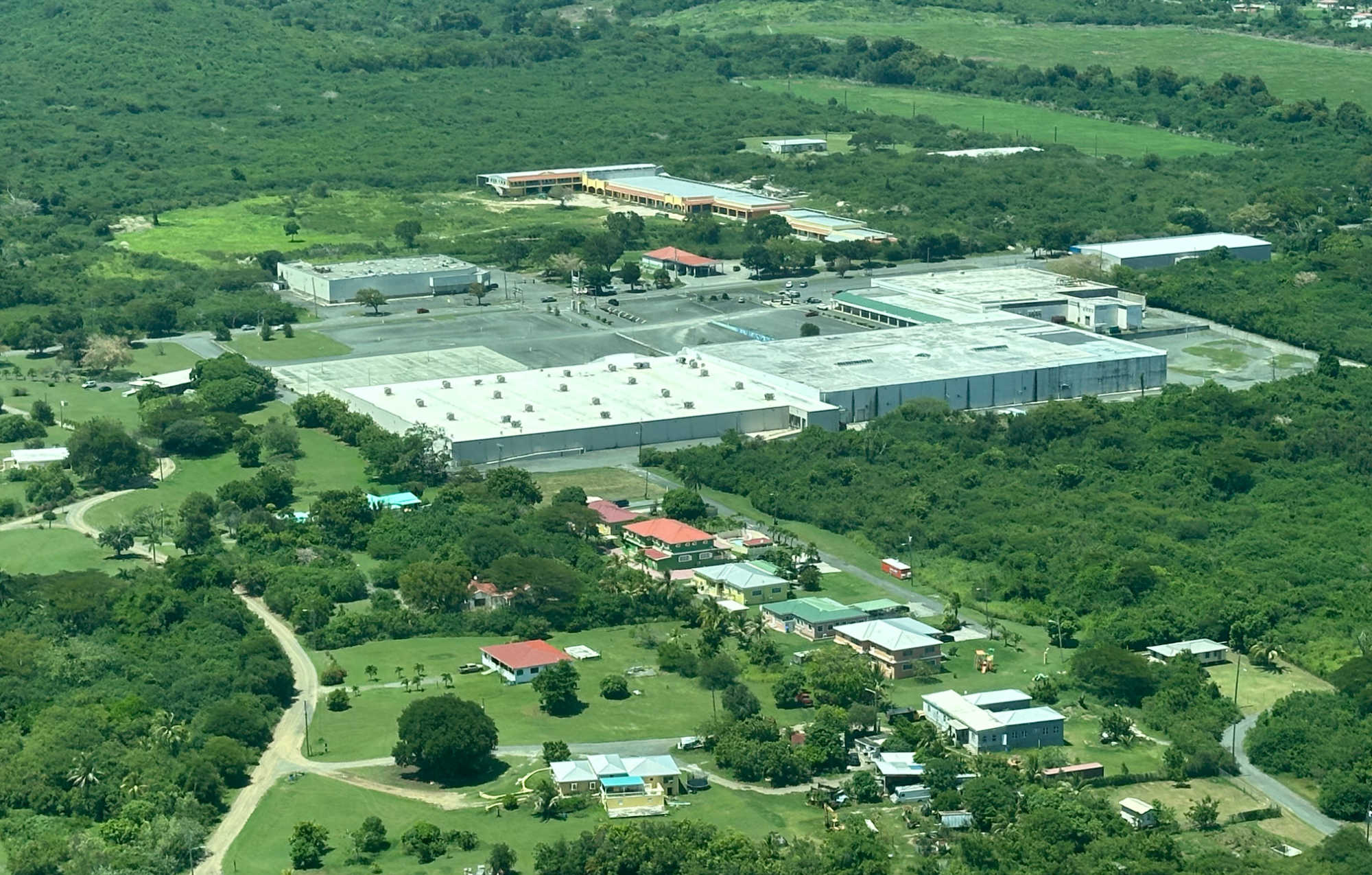 Aerial view of Sunshine Shopping Center, also known as the Mall of St. Croix, in Estate Cane Garden on St. Croix, surrounded by undeveloped land and nearby residences.